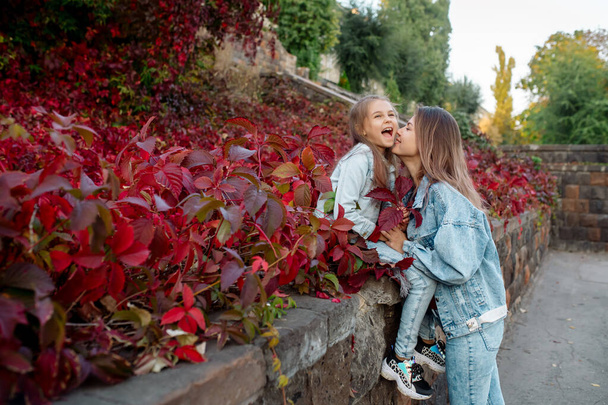 piękna młoda rodzina mama przytula jej ładna córka na spacer w parku jesienią - Zdjęcie, obraz