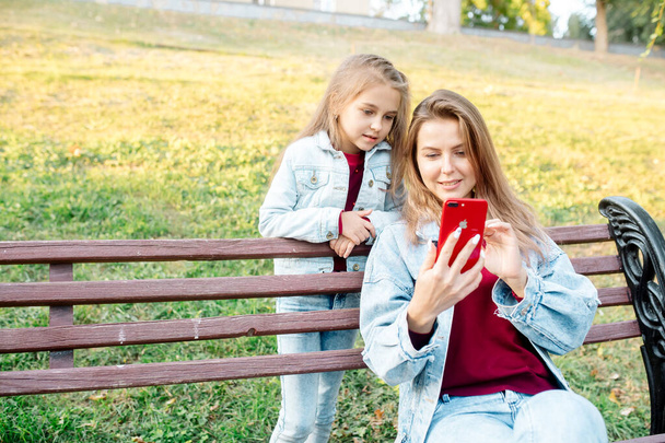 A young mother and her daughter 7 years old take a joint photo on the phone - Fotografie, Obrázek