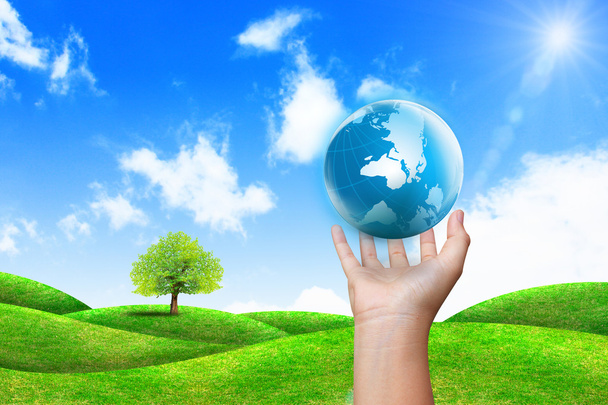 global en mano y hierba verde con cielo azul
 - Foto, Imagen