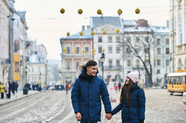 Una pareja de jóvenes de moda pasea por la ciudad en Navidad - Foto, imagen