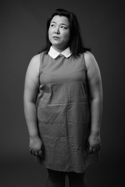 Mooie overgewicht Aziatische vrouw tegen grijze achtergrond - Foto, afbeelding