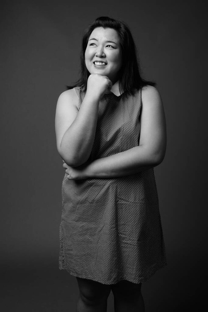Beautiful overweight Asian woman against gray background - Photo, Image
