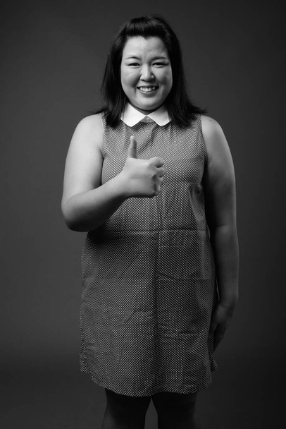 Kaunis ylipainoinen aasialainen nainen harmaata taustaa vasten - Valokuva, kuva