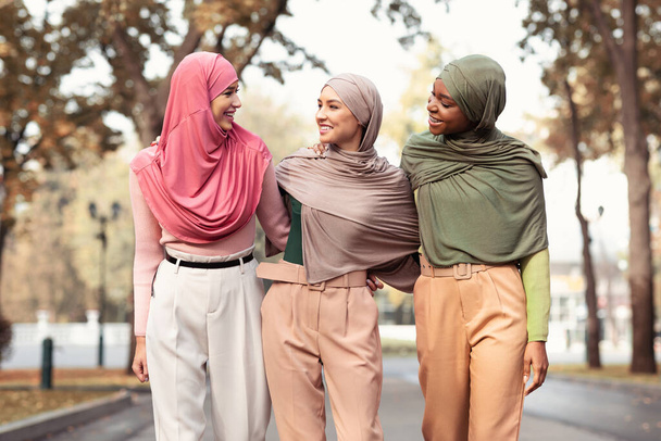 Kolme musliminaista yllään hijab ja moderni vaatteet kävely ulkopuolella - Valokuva, kuva