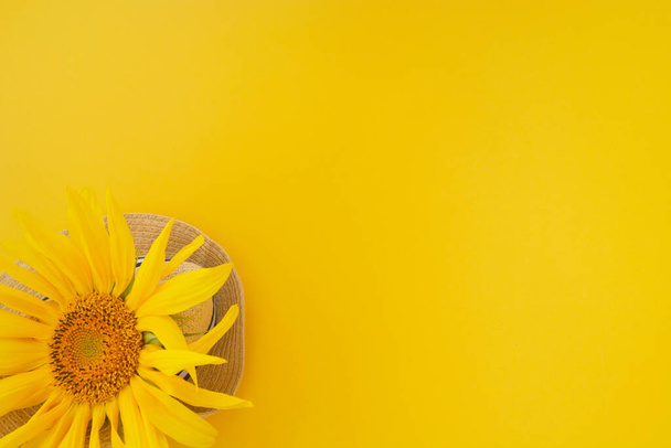 Sombrero amarillo de girasol y paja sobre fondo amarillo. Copiar espacio. Concepto de verano. - Foto, imagen