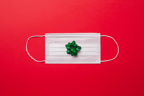 Christmas decoration on a protective medical face mask for Covid-19, coronavirus, on red background - Photo, Image