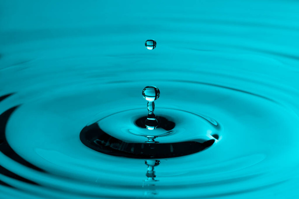 Perfektní kapka vody stříkající do hladké vody způsobuje vlnky - Fotografie, Obrázek