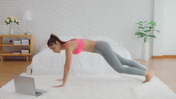 Athletic Healthy Asian woman in sportswear workout excercise online course at home in bedroom quarantine due COVID-19 pandemic,Young woman with slim body cardio aerobic exercises lifestyle concept - Materiaali, video