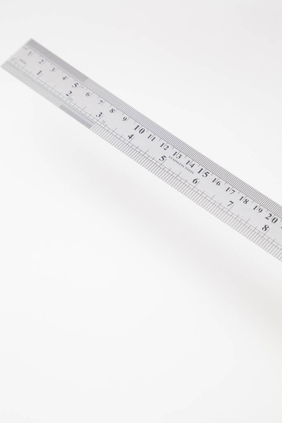 Hoekige roestvrijstalen liniaal met inches en centimeters op wit - Foto, afbeelding