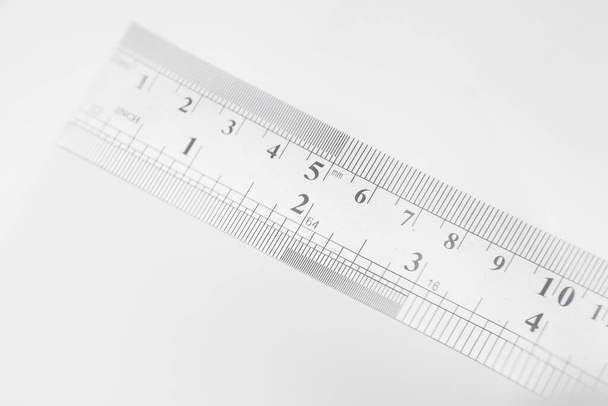 Closeup of angled stainless steel ruler with inches and centimeters on white - Photo, image