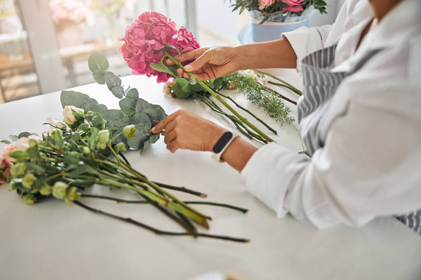 Обережні руки флориста, що розставляє квіти в композицію
 - Фото, зображення