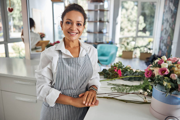 Professional lady in an apron working in a flower shop - Фото, зображення