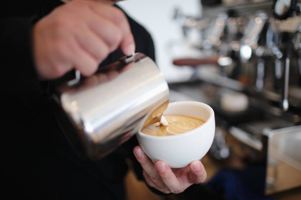 Männliche Hände gießen Milch ein und bereiten Cappuccino-Kaffee zu - Foto, Bild