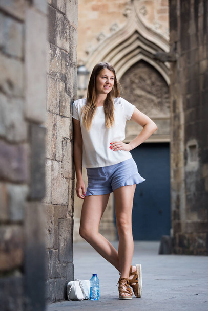 Young woman standing near old stone wall - Foto, Bild