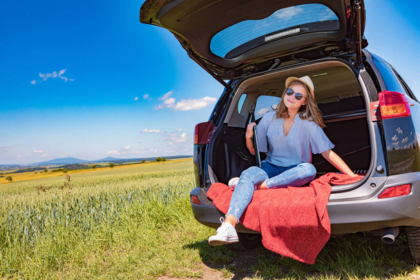 uma jovem com o laptop em um carro na viagem pelo campo - Foto, Imagem