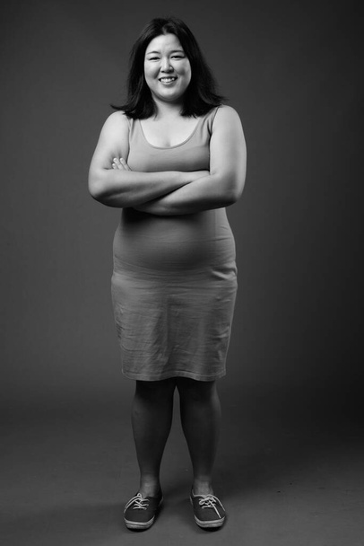 Beautiful overweight Asian woman against gray background - Foto, afbeelding