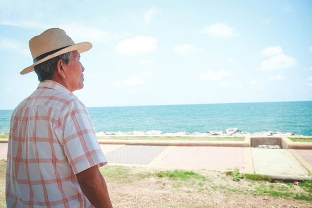 An elderly man wearing a hat looking at the beautiful sea - Photo, Image
