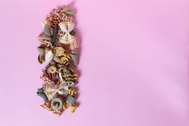 Italian pasta of different shapes and colors on a pink background. Copy space. Selective focus. Top view. - Photo, Image