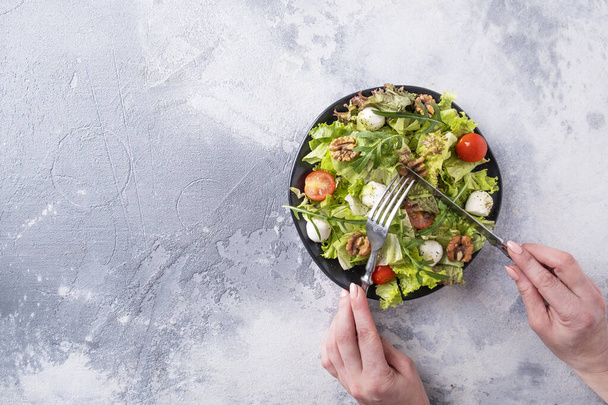 Woman is eating healthy salad on light background. Healthy food concept. Top view, text space - Foto, Imagem