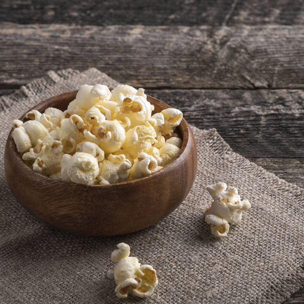 Classic salty popcorn in a wooden bowl. Closeup - 写真・画像