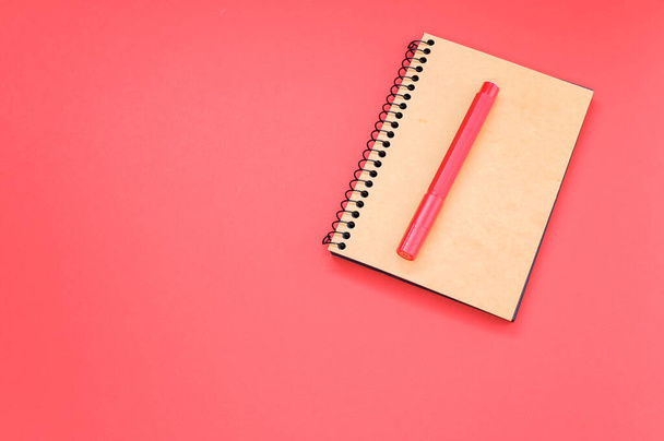 A high angle shot of a notebook and a red marker on a red surface - Foto, immagini