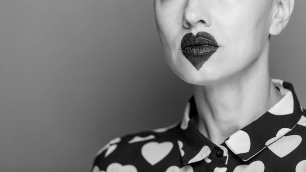 beautiful young woman with unusual make-up, black heart on lips. black and white - Photo, image