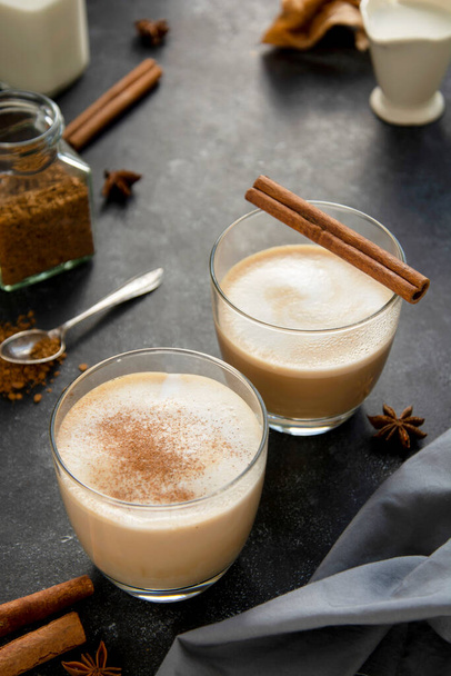 Hot chocolate with whipped cream in glass isolated with cinnamon stick, on dark background - Φωτογραφία, εικόνα