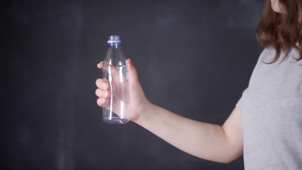 Mittendrin Aufnahmen einer nicht wiederzuerkennenden Frau, die eine Plastikflasche in den Händen hält und diese aus Protest auf dunklem Hintergrund zerknüllt - Filmmaterial, Video
