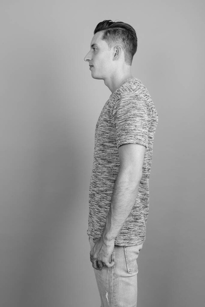 Jovem homem bonito vestindo camisa cinza contra fundo cinza - Foto, Imagem