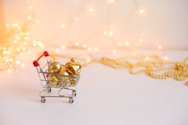 Lebensmittelkorb mit goldenen Weihnachtskugeln auf dem Hintergrund leuchtender Lichter. Verkaufskonzept für das neue Jahr - Foto, Bild