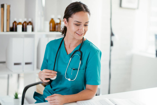 glimlachende vrouwelijke arts in medische jurk met stethoscoop  - Foto, afbeelding
