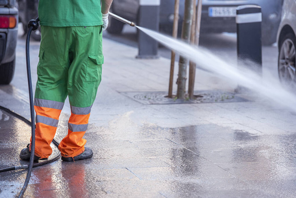 A worker cleaning the streets with a pressurized bleach water gun - the concept of coronavirus prevention - Фото, зображення