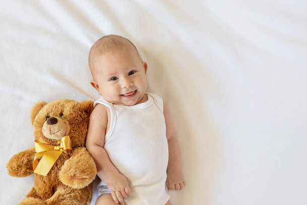 Baby plays with teddy bear against white background. Selective focus. People. - Fotografie, Obrázek