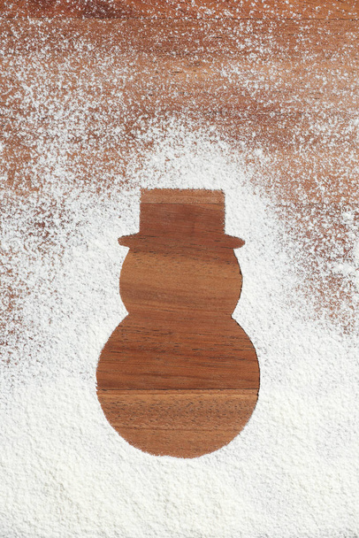 Sylwetka tradycyjnego minimalistycznego bałwana Bożego Narodzenia w kapeluszu, drewnie i śniegu, przestrzeń do kopiowania - Zdjęcie, obraz