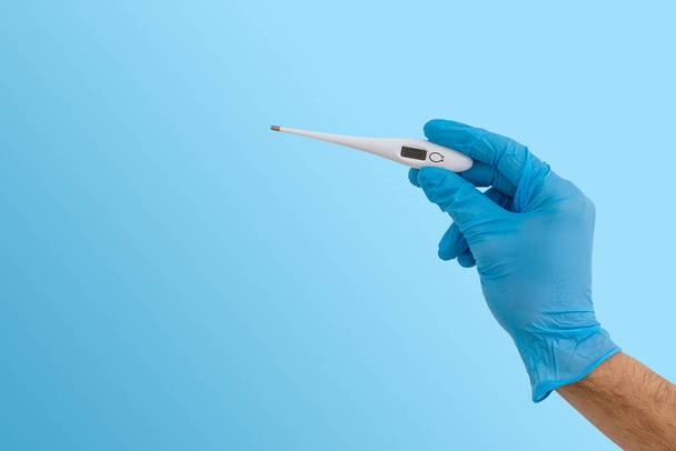 Hands in blue gloves holding a medical thermometer - Фото, зображення