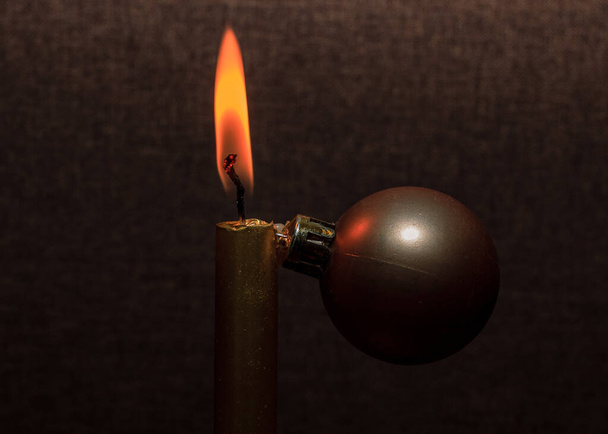 Gold color shiny candle fire and orange flame, decoration ball, on brown background. Creative christmas tree. - Fotó, kép