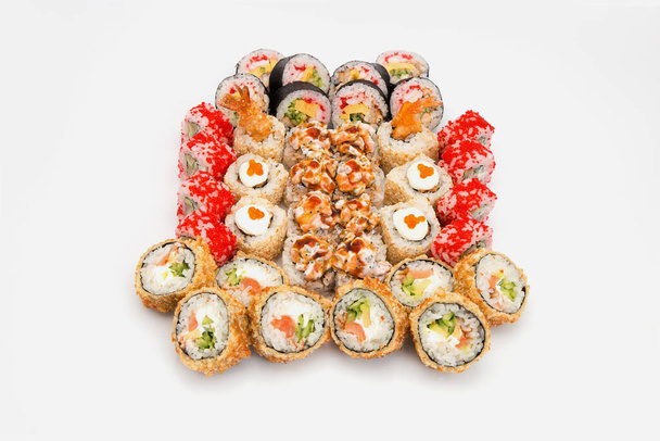 Σετ από κομμάτια ρολό σούσι με θαλασσινά και ωμό ψάρι. Futomaki και tempura sushi roll. Ποικιλία από ανατολικές φέτες τροφίμων με διαφορετικά συστατικά θαλασσινά απομονώνονται στο παρασκήνιο.  - Φωτογραφία, εικόνα