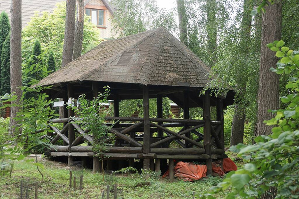 Ein großer schwarzer Holzpavillon steht inmitten grüner Vegetation und Bäume im Park - Foto, Bild