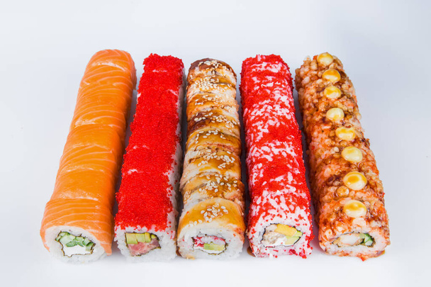 Zestaw pięciu kawałków sushi rolki z owoców morza i surowego filetu rybnego. Różnorodność wschodnich plasterków żywności. Różne japońskie przekąski odizolowane na tle. Smaczne jedzenie z Azji Wschodniej serwowane na szarym tle  - Zdjęcie, obraz