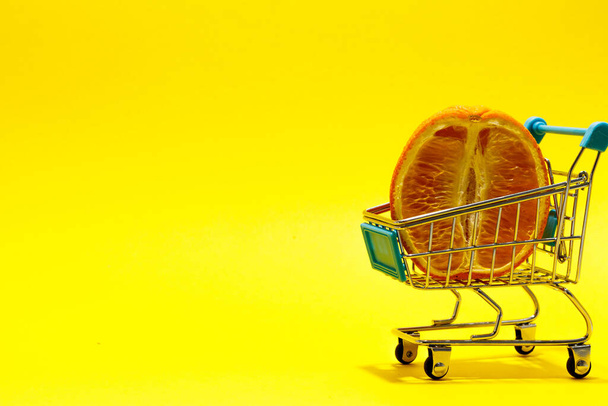 ?zkorumpované oranžové v supermarketu vozíku na žlutém pozadí. online nákupní koncept - Fotografie, Obrázek