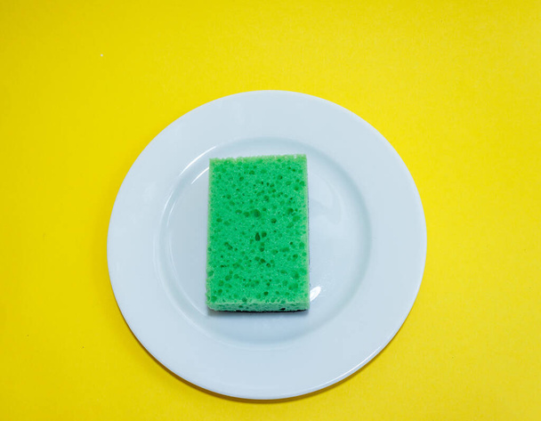 Cleaning sponge on a white plate on a yellow background.Flat lay - Photo, Image