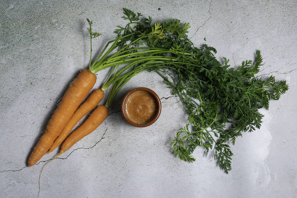 Three carrots with leaf and a healthy carrot puree in a clay bowl Healthy food conceptual - 写真・画像