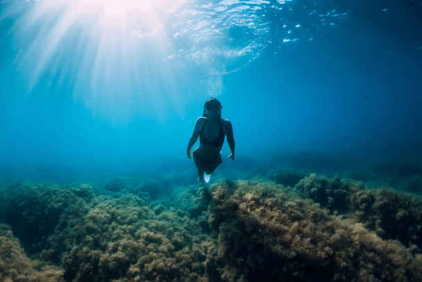 Donna subacquea libera con pinne bianche scivola sott'acqua con incredibili raggi di sole. Immersioni subacquee nell'oceano - Foto, immagini