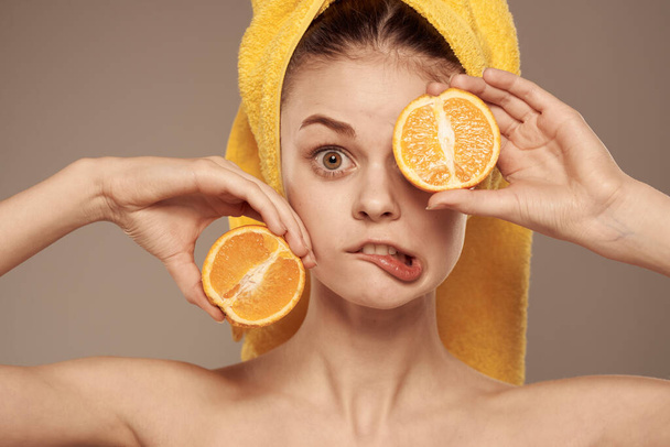 mulher em uma toalha amarela em sua cabeça laranjas close-up fundo bege - Foto, Imagem