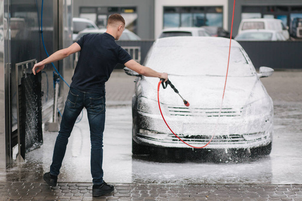 Cleaning car using active foam. Man washing his car on self car-washing - Zdjęcie, obraz