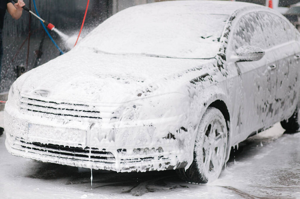 Limpieza de coches con espuma activa. Hombre lavando su coche en auto-lavado - Foto, Imagen