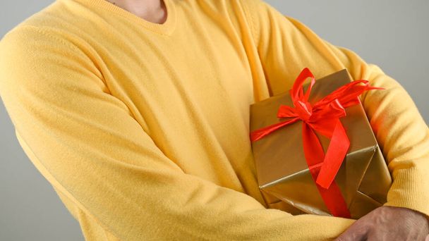 A man holding a gift box with a red bow. High quality photo - Photo, image