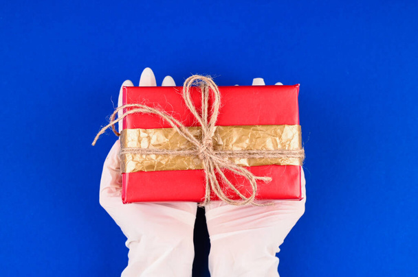 Девушка держит подарочную коробку в резиновых перчатках. Высокое качество фото - Фото, изображение