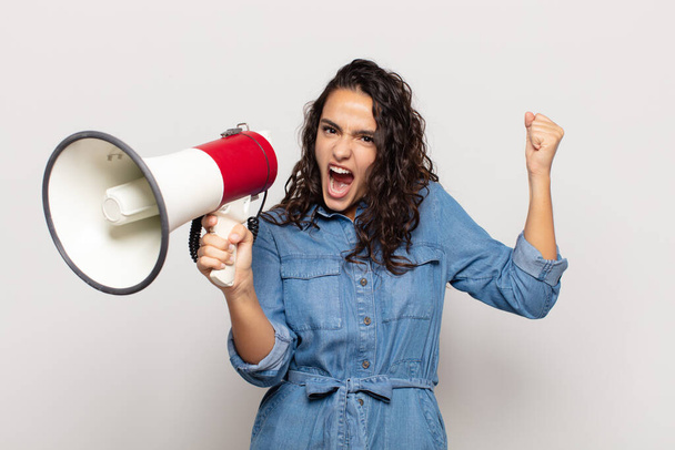 young hispanic woman shouting aggressively with an angry expression or with fists clenched celebrating success - Foto, Imagem