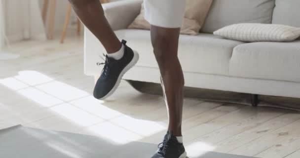 Atletyczny, afrykański mężczyzna energicznie biegający w domu, śledzący strzały od nóg do twarzy - Materiał filmowy, wideo